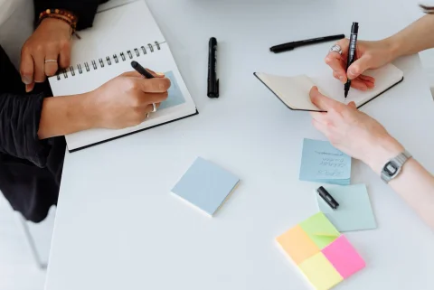 Hands taking notes together during a collaborative work session