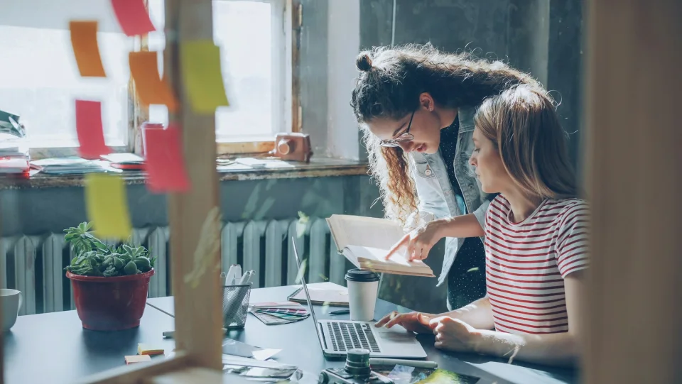 Two women sharing ideas while working together at a laptop